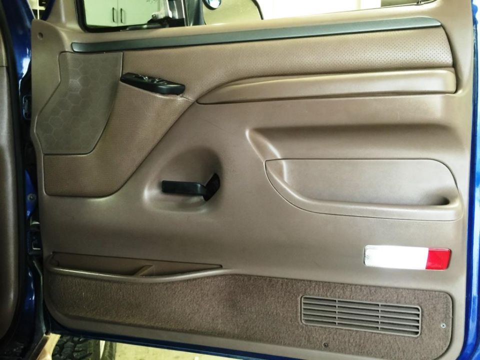 1996 Ford Bronco interior door panel with brown carpet and speaker grille