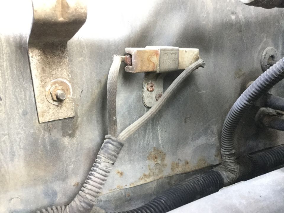 Close-up of a corroded electrical connector with frayed wires in a vehicle's engine bay