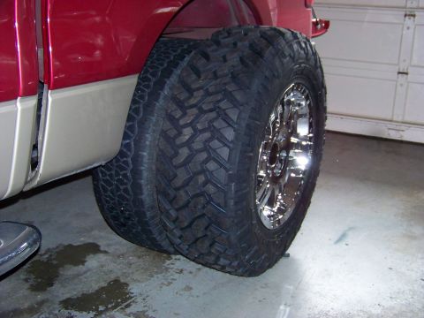 2005 Ford F-150 - Close-up of the dual rear wheels and tires on a red truck, showing off the aggressive tread pattern.