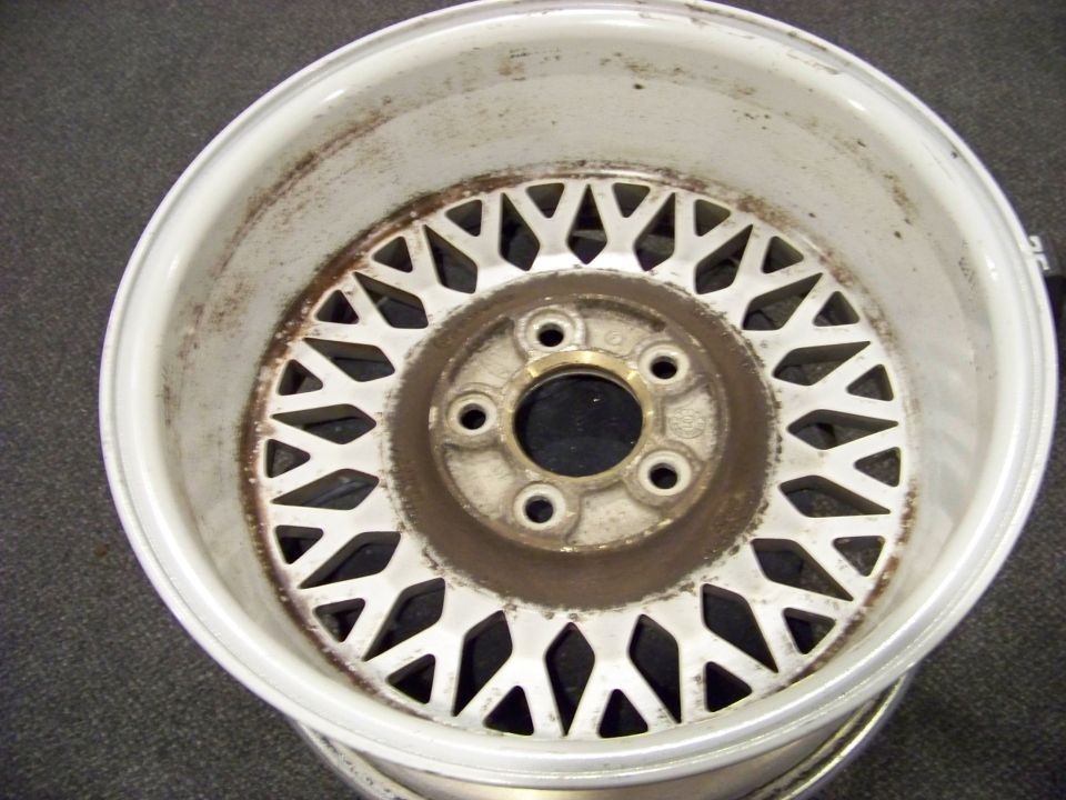 White mesh alloy wheel with rust on the rim and center hub