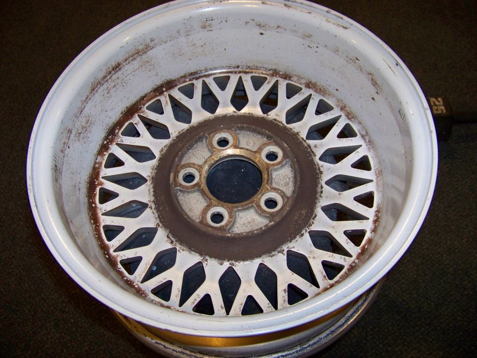White mesh wheel with rust on the rim and center cap