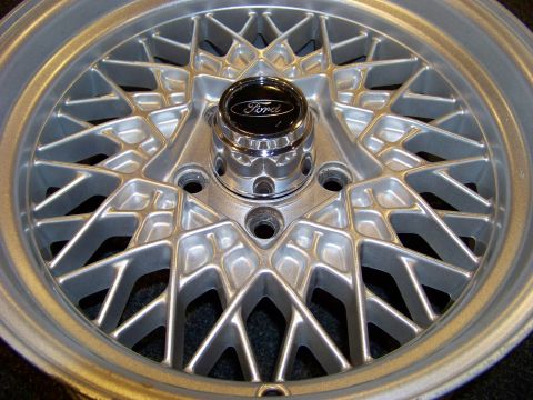 1999 Mercury Grand Marquis - A close-up view of a silver mesh wheel with a Ford logo on the center cap.