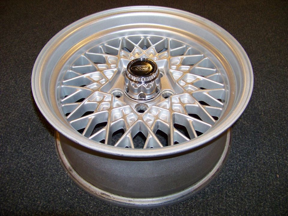 Silver mesh-spoke alloy wheel with Ford center cap, on a dark surface