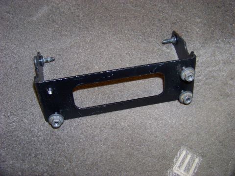 1999 Mercury Grand Marquis - A metal bracket with a rectangular cutout is shown on a carpeted surface.