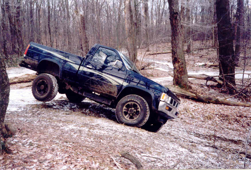 Dark blue pickup truck on a wooded trail, front 3/4 view