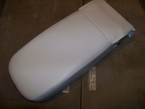 1999 Mercury Grand Marquis - Close-up of a light gray armrest, possibly from a vehicle's interior, resting on brown carpet with embossed lettering.
