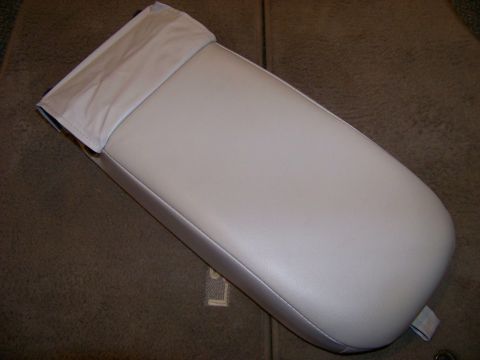 1999 Mercury Grand Marquis - A close-up view of a car's center console armrest, showing its light tan leather upholstery and a fabric flap detail.