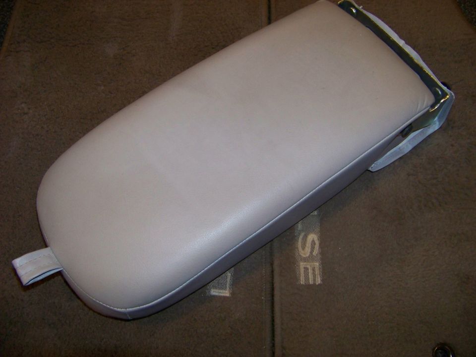 Beige vinyl armrest with a fabric loop on the left end, resting on a brown textured surface