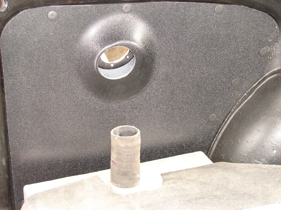 Close-up of a textured interior panel with a circular cutout and a short hose protruding