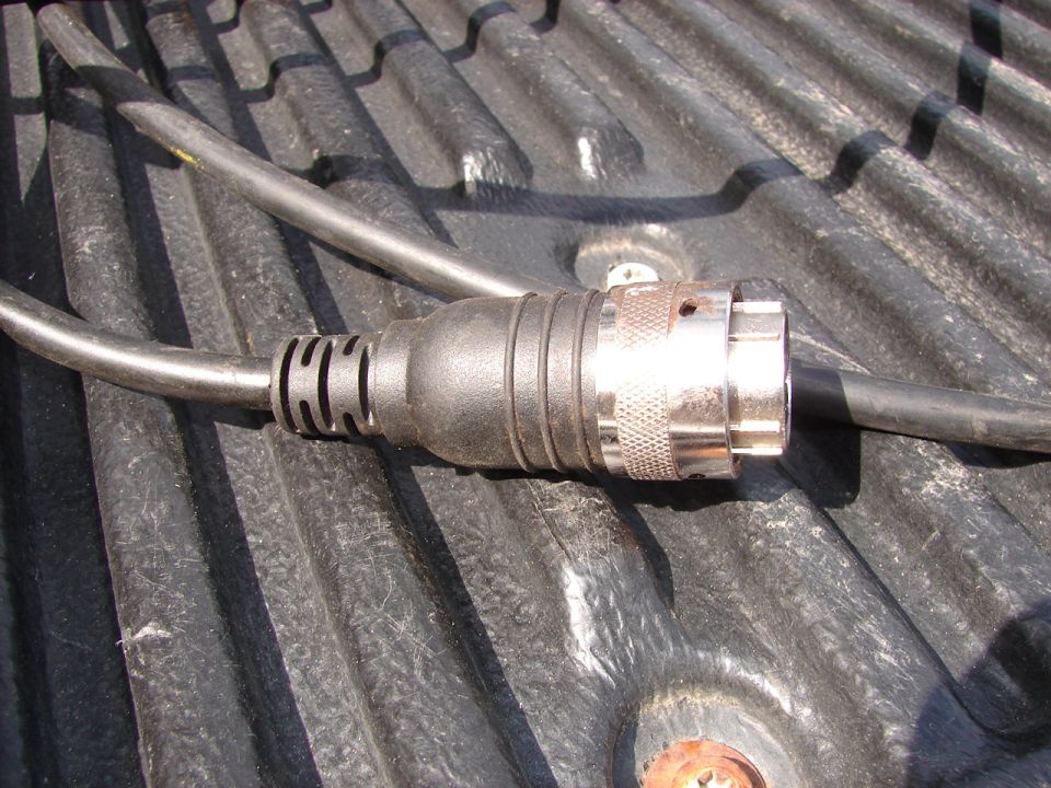 Metal and black plastic electrical connector with cable on ribbed black surface