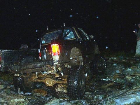 1978 Ford Bronco - A black pickup truck is shown off-roading at night over a rocky surface.