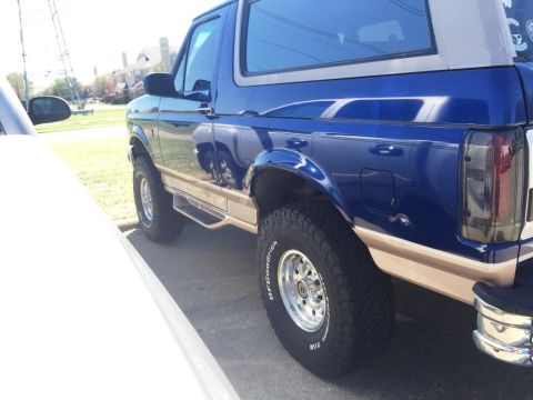 1996 Ford Bronco - Side view of a blue 1996 Ford Bronco with tan lower body trim and aftermarket wheels.
