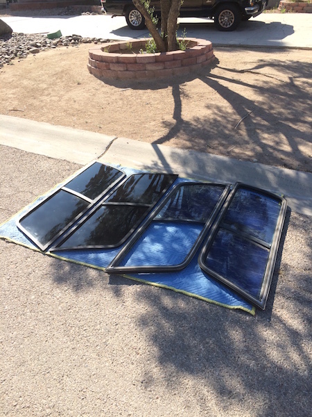 1981 Ford Bronco - Several car windows are laid out on a blanket on the ground, with a truck visible in the background.
