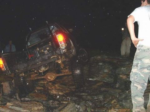 1978 Ford Bronco - Off-road vehicle stuck on rocks at night, with people standing nearby.