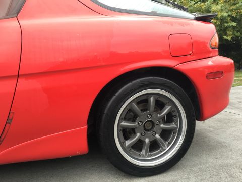 1993 Mazda MX-3 - Rear view of a red 1993 Mazda MX-3 showing the quarter panel, wheel, and spoiler.