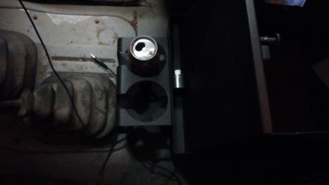 1985 Ford Bronco - Interior view of a vehicle's cup holder and gear shifter, with a can placed inside.