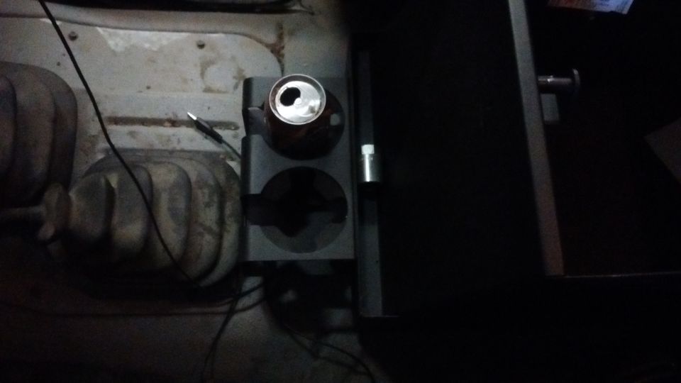 Vehicle interior showing a cup holder with a can and a gear shifter