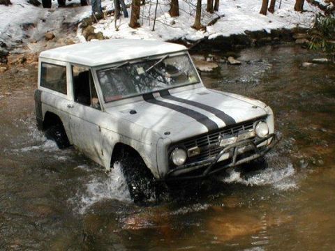 1993 Ford Bronco - First-generation Ford Bronco navigating a stream, showing its off-road capability.