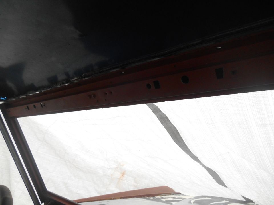 Interior shot of a vehicle, looking up at the headliner and windshield frame. Some parts appear to be under restoration