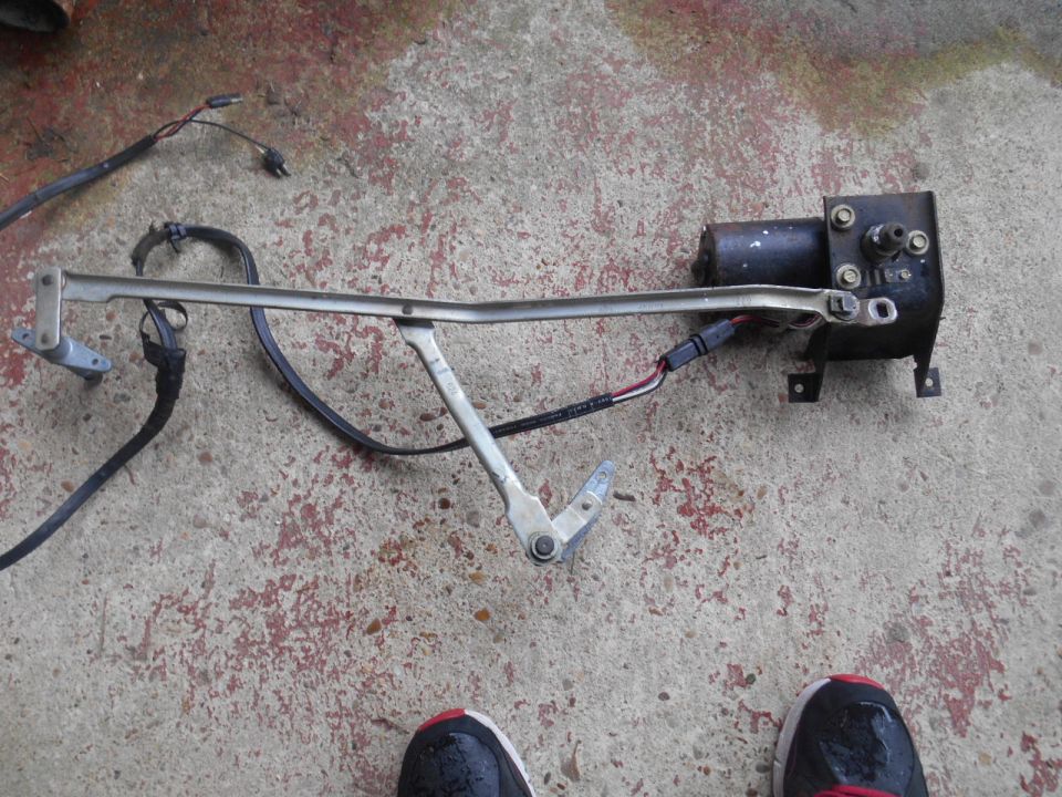 Windshield wiper motor assembly with linkage and wiring on concrete