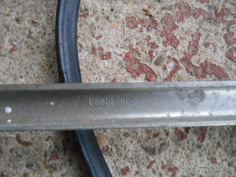 1972 Ford Bronco - A metal part with stamped numbers 88988 83 is shown against a concrete background.
