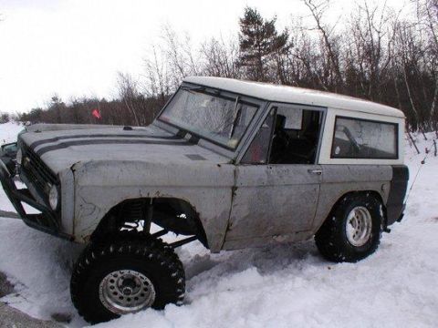 1993 Ford Bronco - This lifted Ford Bronco, likely from the early 1970s, is shown in a snowy environment with aftermarket modifications.