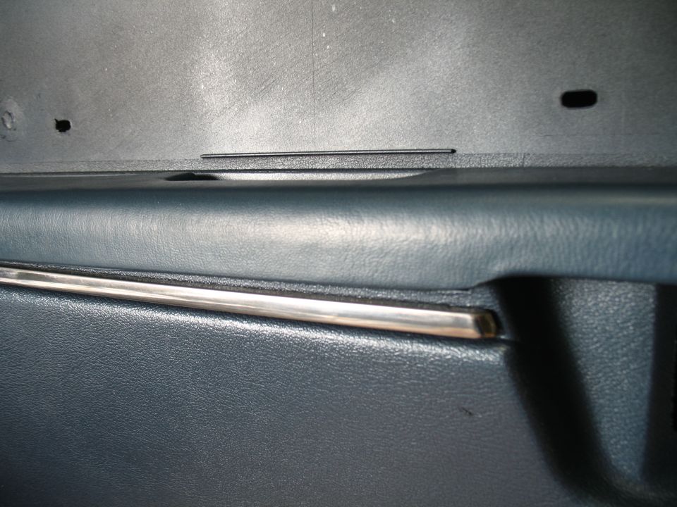 Close-up of dark blue car door panel with chrome trim strip