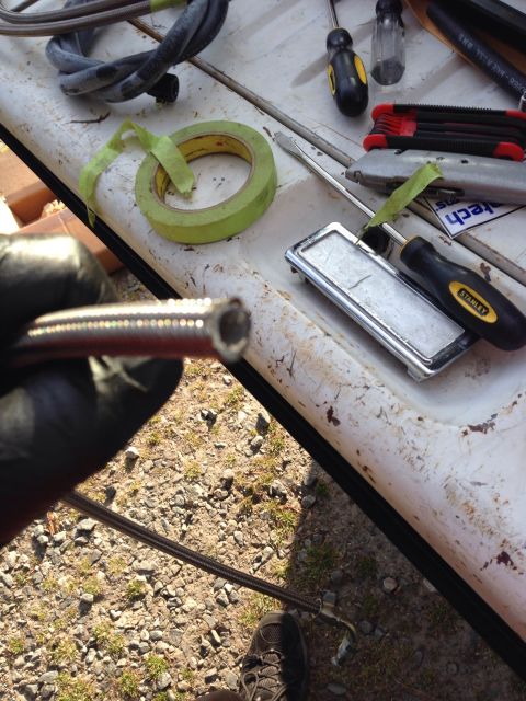 1979 Ford Bronco - Tools and a braided hose are laid out on a surface, possibly for automotive repair.