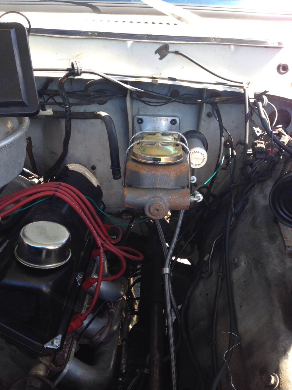 Engine bay with brake master cylinder and red spark plug wires
