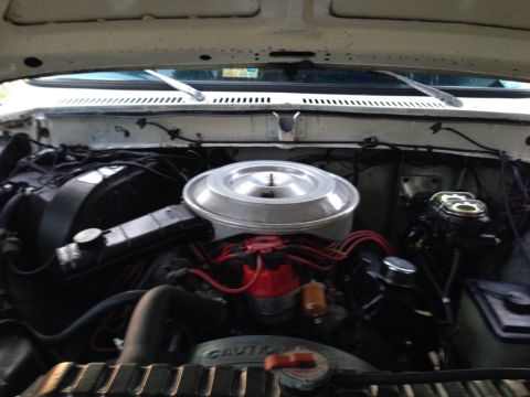 1979 Ford Bronco - The engine bay of a white vehicle is visible, showing various engine components and wiring.