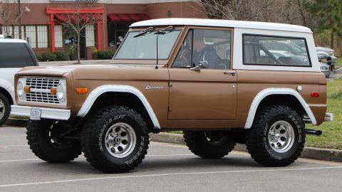 1979 Ford Bronco - This 1979 Ford Bronco features a classic brown and white color scheme and is presented in a 3/4 front view.