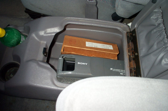 Open gray center console holding a Sony 10-disc CD changer and a cardboard box