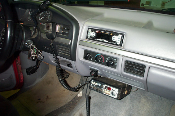 Gray dash interior with aftermarket stereo and CB radio with coiled mic cord below the dash