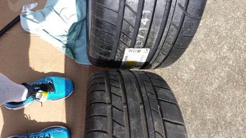 1976 Ford Ranchero - Close-up view of two tires, one with a white label and markings, on a surface with a shoe and cloth.