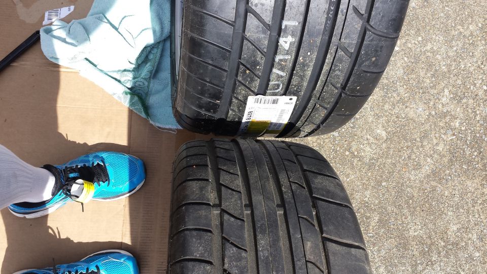 Two performance tires on a cardboard surface with a blue shoe and a cloth