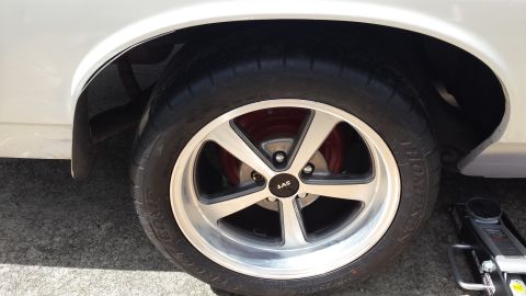 1976 Ford Ranchero - Close-up of a white vehicle's wheel, an SVT center cap and red brake caliper, with a tire jack visible.
