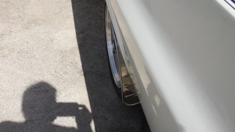 1976 Ford Ranchero - A close-up, side view of the rear wheel well area of a white vehicle, showing a polished metal wheel and a custom mud flap or fender extens…