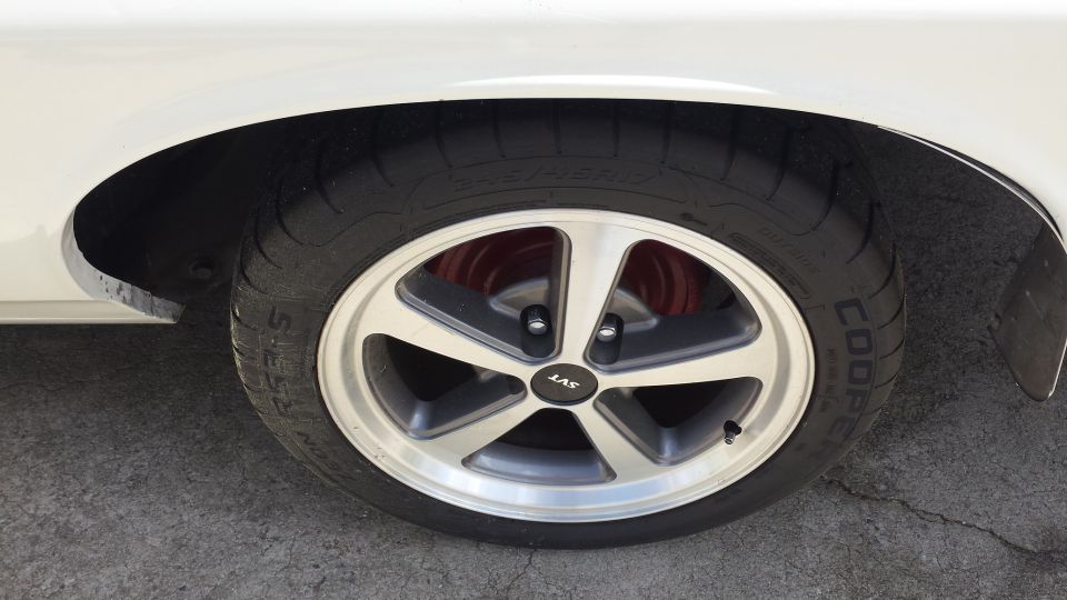 White vehicle's front passenger side wheel with silver SVT wheel and Cooper tire.
