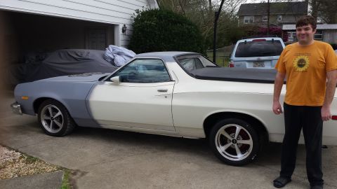 1976 Ford Ranchero - A man stands next to a two-tone white and gray Ford Ranchero with a black tonneau cover. The vehicle is parked in a driveway in front of a…