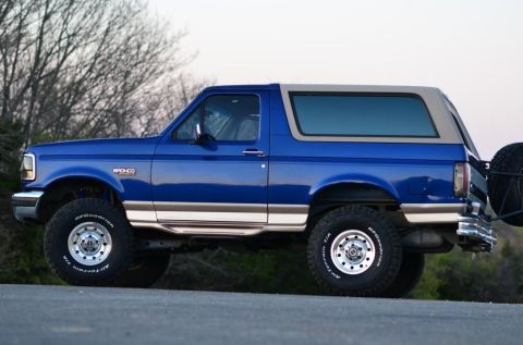 1996 Ford Bronco - This 1996 Ford Bronco is shown in profile, a blue body with a tan removable top and a spare tire mounted on the rear.