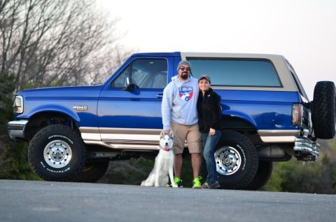 1996 Ford Bronco - A couple and their husky pose with a blue 1996 Ford Bronco.