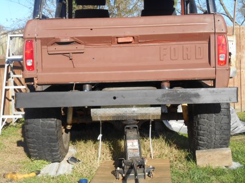 1972 Ford Bronco - The rear of a brown Ford Bronco is shown, lifted by a jack and supported by blocks. The tailgate has the "FORD" lettering embossed on it an…