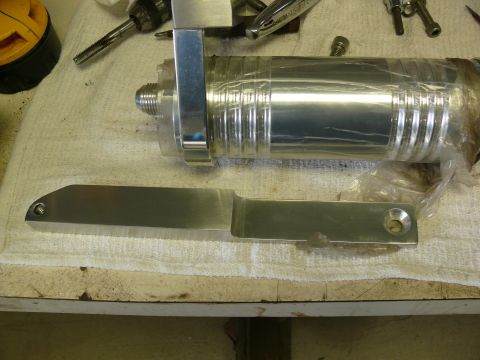 Metal part with blade-like end and threaded hole on cloth near cylindrical object.