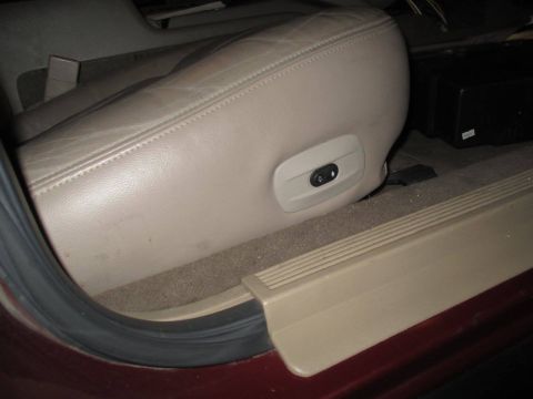 2004 Ford Crown Victoria - Interior view of a tan leather seat with power controls and a door sill, consistent with a 2004 Ford Crown Victoria.