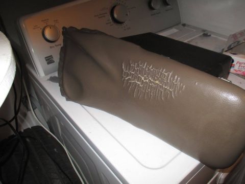 2004 Ford Crown Victoria - This image shows a damaged car armrest with significant cracking and wear on its surface.