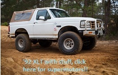 1992 Ford Bronco - White 1992 Ford Bronco XLT with a soft top and off-road bumper, parked outdoors.