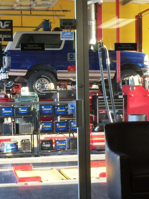 1996 Ford Bronco - A blue and white 1996 Ford Bronco is shown on a car lift in a service bay.