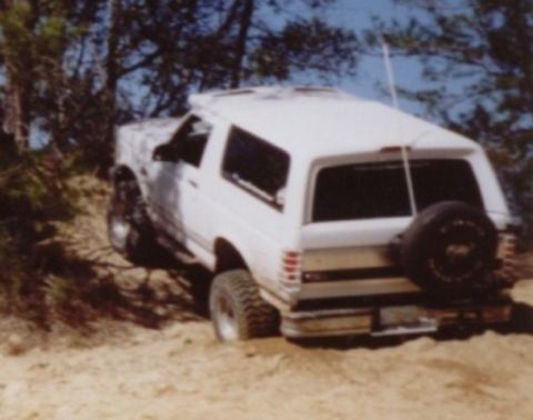 1995 Ford Bronco - White 1995 Ford Bronco navigating a sandy, wooded trail.