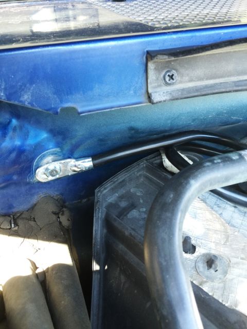 1996 Ford Bronco - A close-up view of wiring and components within the engine bay of a blue vehicle.