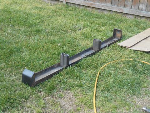 1972 Ford Bronco - A custom metal bumper, likely for a truck or SUV, rests on a grassy lawn next to a wooden fence.